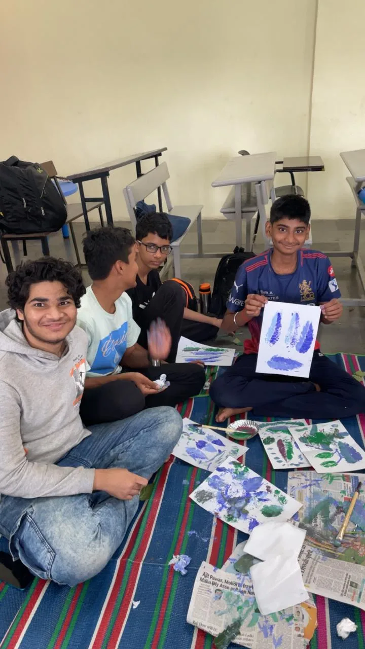 Students seated together with leaf-print artwork made during an art activity