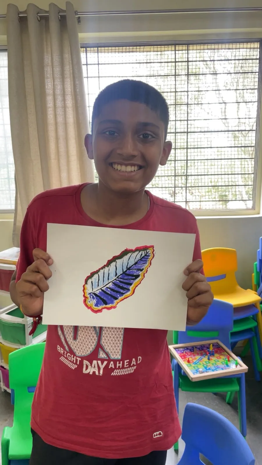 Student holding a colourful leaf-print artwork