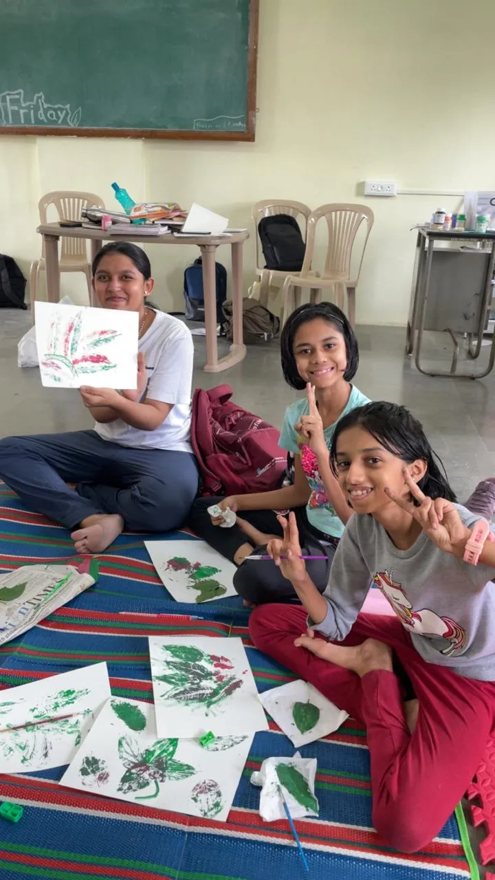 Students displaying leaf-print artwork after a group art activity