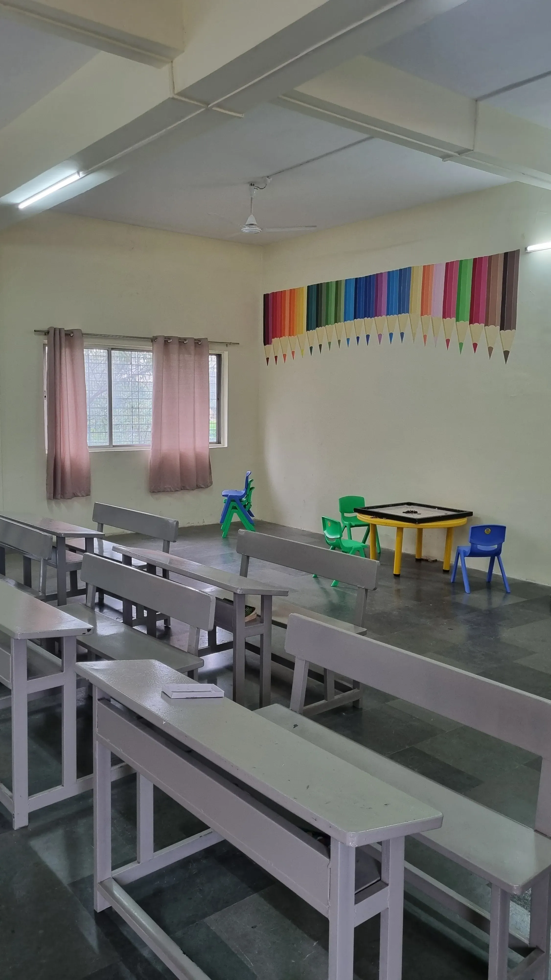 Classroom with bench seating, colourful pencil wall art and a small activity table