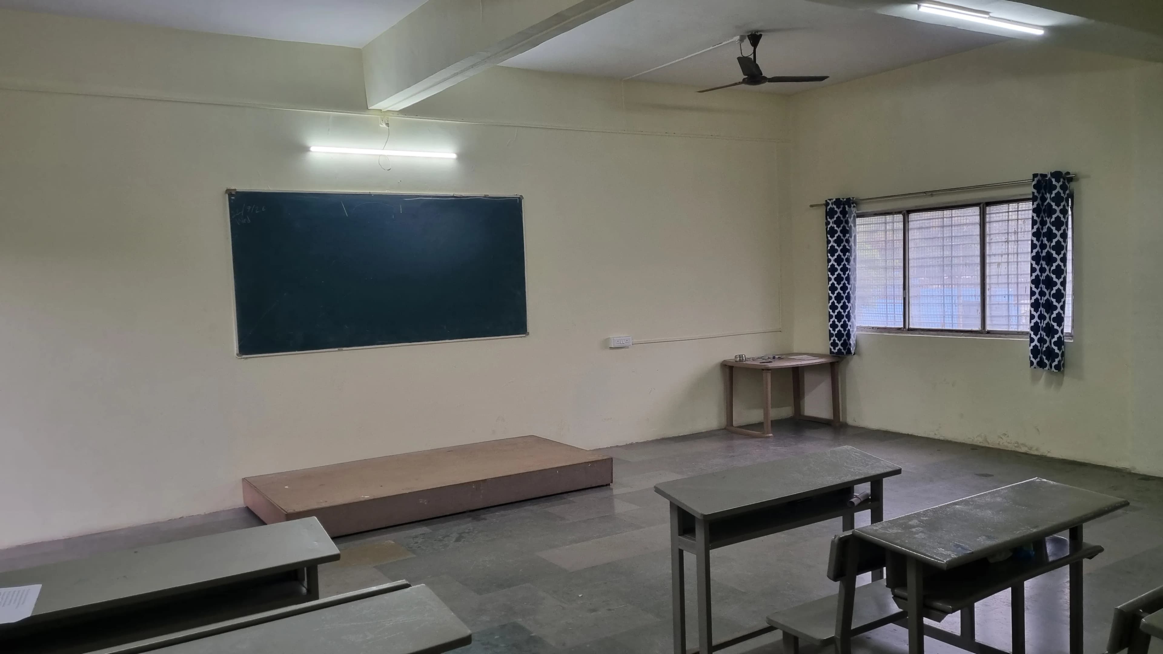 Classroom with bench seating, a blackboard and a raised teaching platform