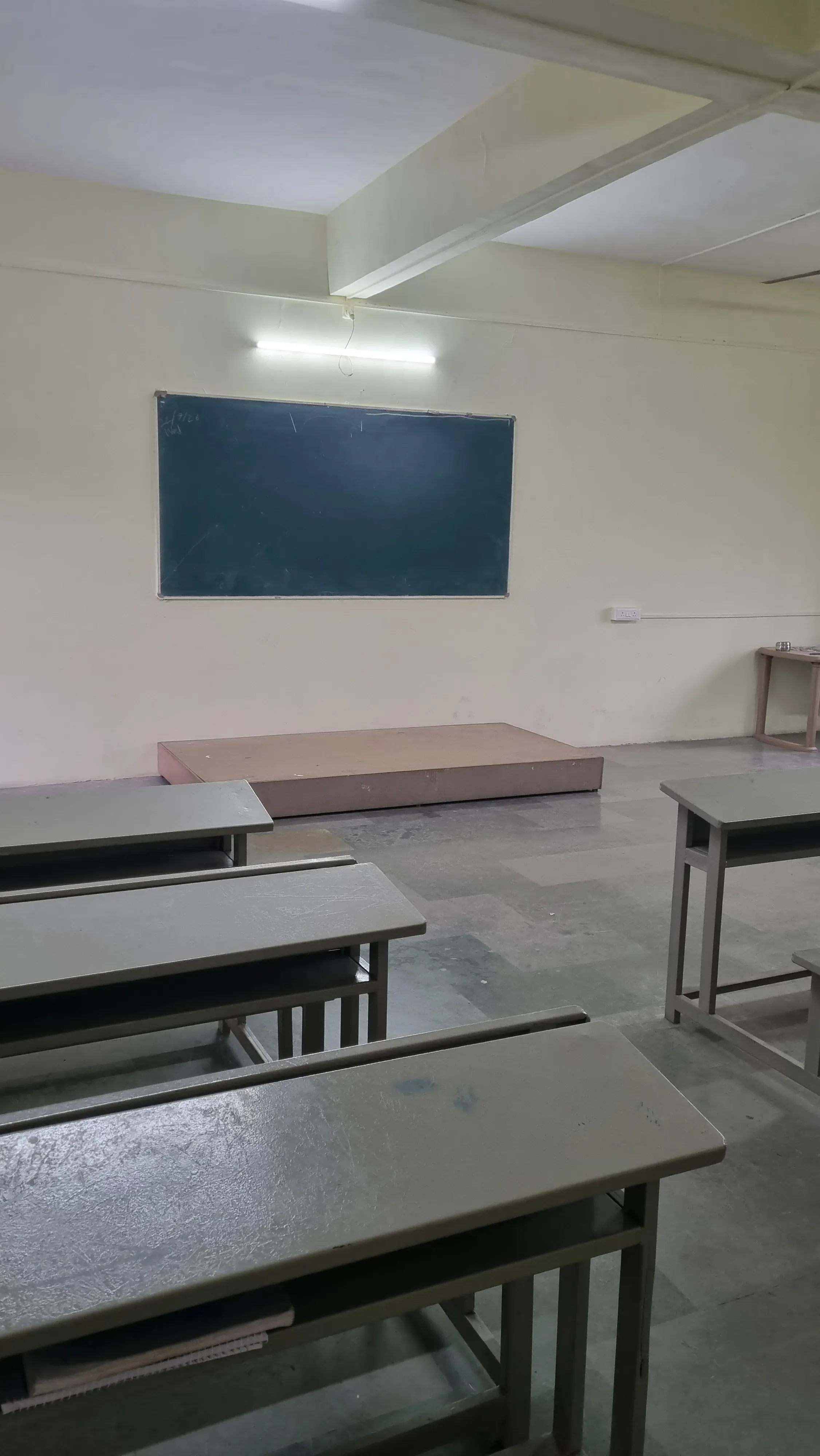 Classroom desks facing a blackboard and low teaching platform